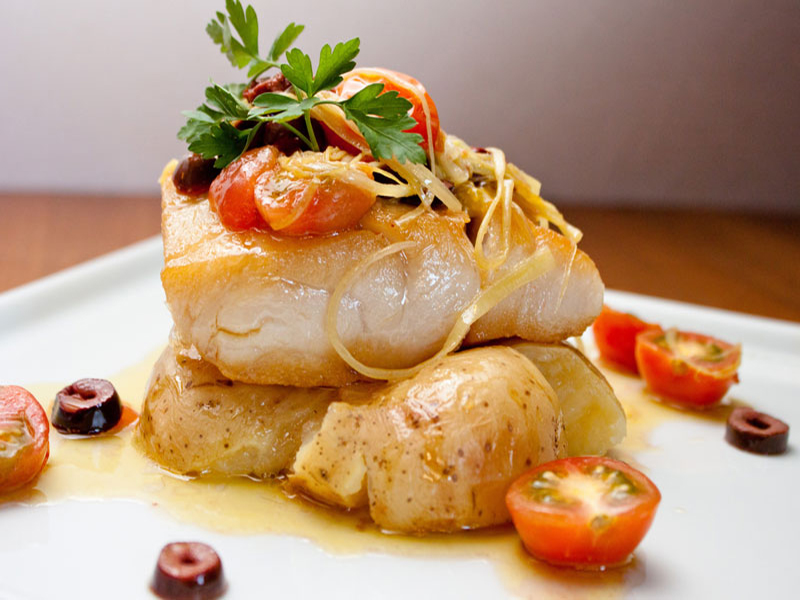 Close-up of appatizing white fish with potatoes and cherry tomatoes