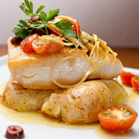 white fish with potatoes, cherry tomatoes, garnish, and sauce