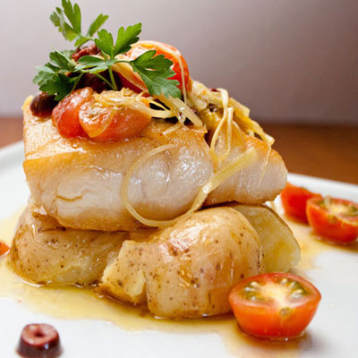 close-up of white fish with potatoes and cherry tomoatoes